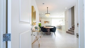Una cocina moderna con comedor, que incluye una araña, una mesa redonda y sillas negras.