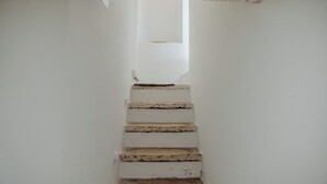 A staircase with white walls and a small window at the top. - Hidden House by Monholiday (Monopoli)