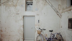 A weathered building with a door, a window, and a bicycle parked outside. - Hidden House by Monholiday (Monopoli)