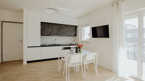 A modern kitchen with white cabinets, a black marble backsplash, and a dining area with a white table and chairs. - Rainbow Relax Home by MONHOLIDAY (Monopoli)