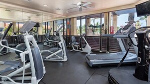 Un gimnasio con cintas de correr, elípticas y un espejo grande.