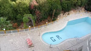 Zwembad met de letters 'GR' in de tegelrand, omgeven door een stenen terras en een gele balustrade.
