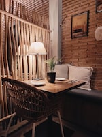 Un rincón comedor acogedor con una mesa de madera, sillas de mimbre, una planta en maceta y un banco acolchado.