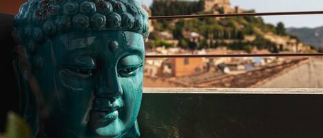 A Buddha statue with a view of a castle in the background.
