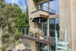 Un bâtiment moderne doté d’un balcon aménagé avec du mobilier d’extérieur et agrémenté d’une lanterne suspendue.