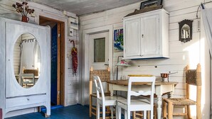 Een kamer met een eettafel, witte stoelen, een spiegel en een kast.