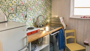 Een kleine keuken met een fornuis, een spoelbak en een raam.