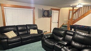 A living room with two black leather sofas, a dartboard, and a foosball table. - Luxury 4BR Ski Retreat, Fireplace, Fire Pit, Mtn Views (Thornton)