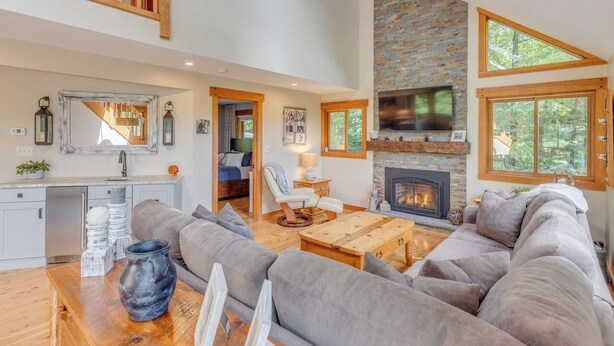 A spacious living room with a large gray sofa, a wooden coffee table, and a fireplace. - Luxury 4BR Ski Retreat, Fireplace, Fire Pit, Mtn Views (Thornton)