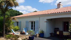 Uma casa com telhado em telhas, varanda coberta e piscina.