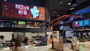 Un restaurant avec une enseigne colorée sur laquelle on peut lire « Mexico MIO » et une enseigne au néon représentant « Summer Beauty ».