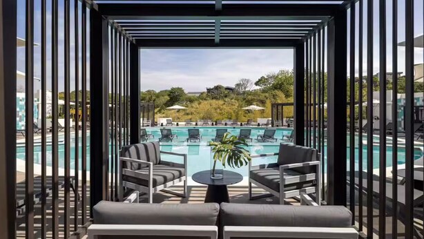 Un espace aménagé au bord de la piscine, comprenant un coin salon couvert, des chaises longues et une vue sur la piscine et le paysage environnant.