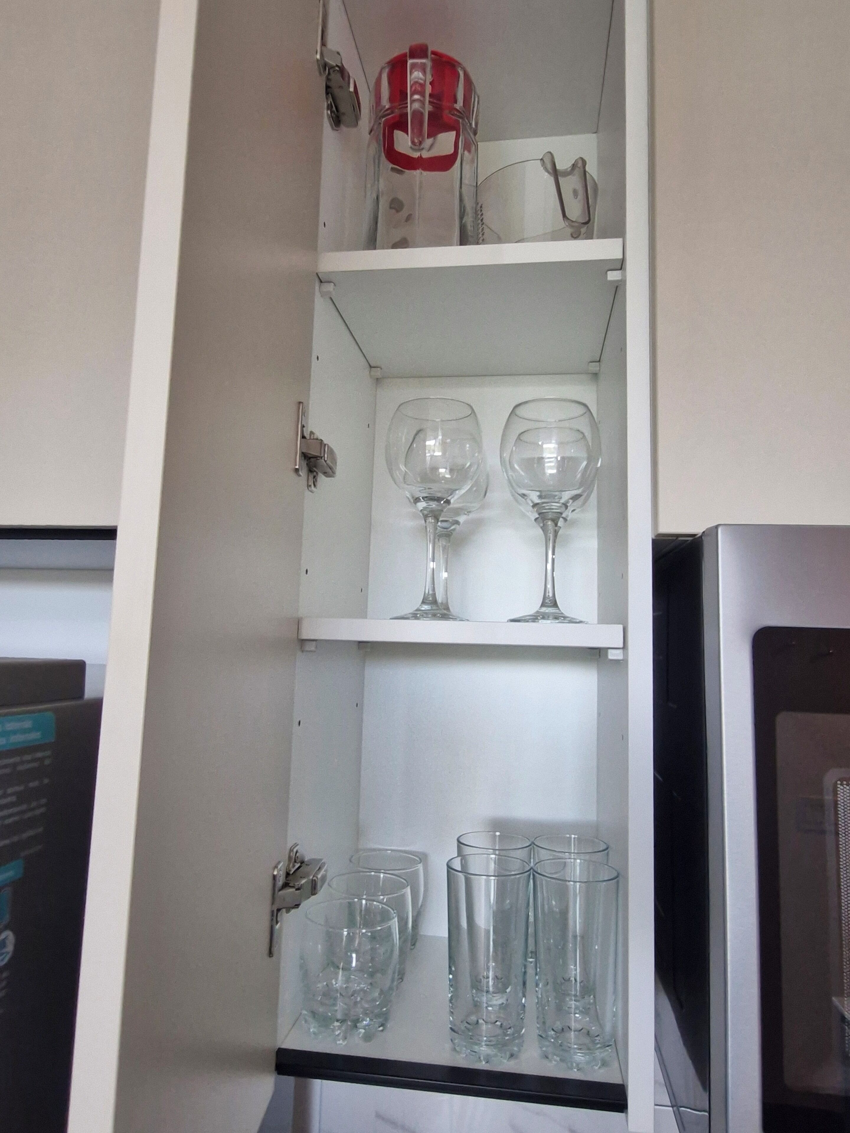 A cabinet with shelves containing wine glasses and a red and white object.