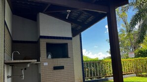 Un espace cuisine extérieur abrité, doté d’un évier et d’un barbecue, et entouré d’un jardin clos.