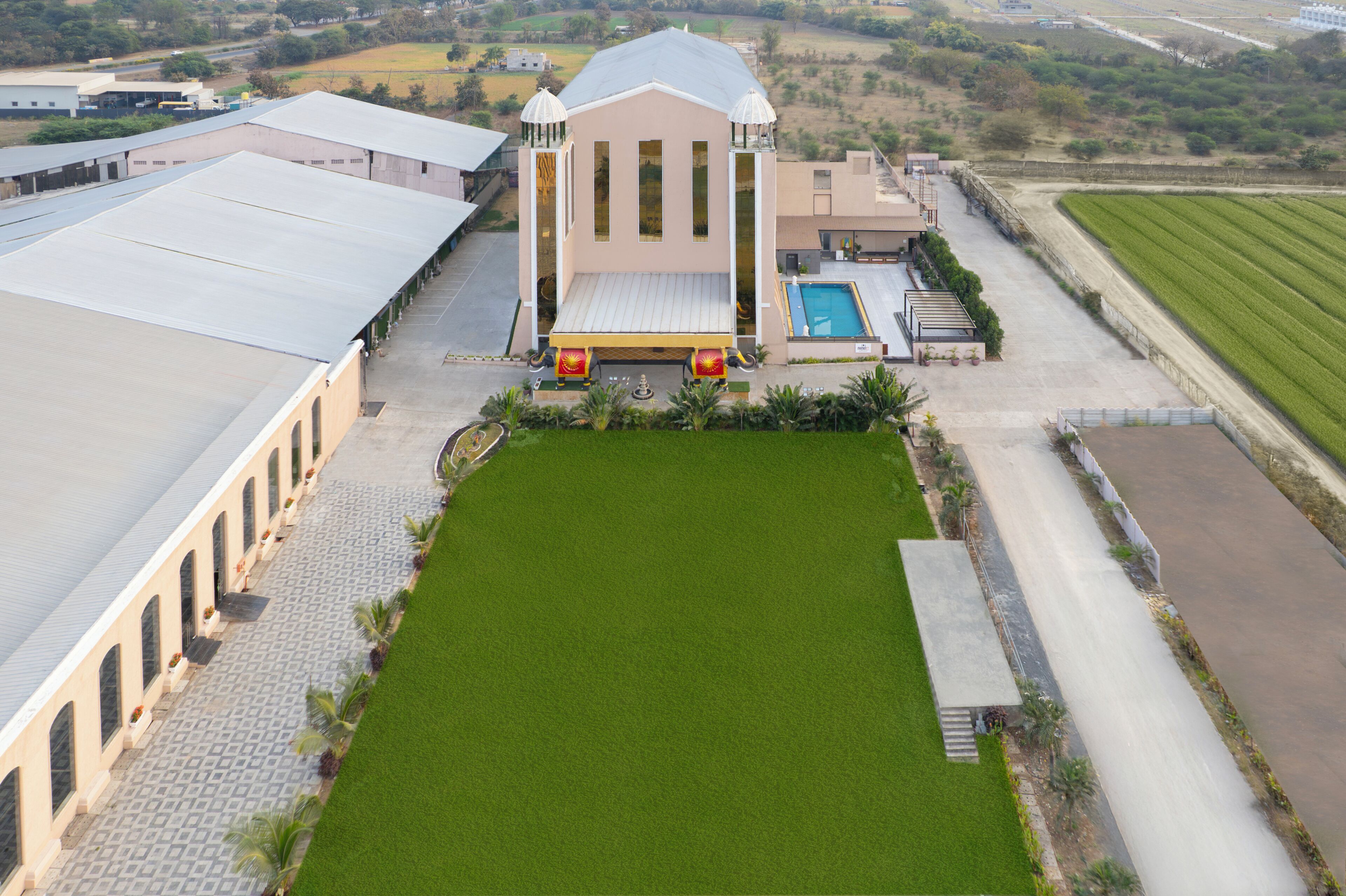 A large building with a central courtyard, a swimming pool, and adjacent fields.