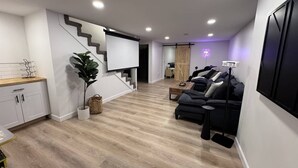 A modern living room with a staircase, a sofa set, and a flat-screen TV.