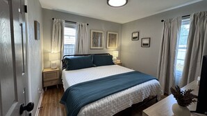 A bedroom with a bed, bedside lamps, a window with curtains, a ceiling light, and a small table with a plant. - Radian Ranch - 2 Kings, Near Derby - Fenced Yard - Pet Friendly. (Wichita)
