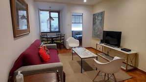 Una sala de estar con sofá, mesa de centro, televisor y comedor con sillas y mesa.