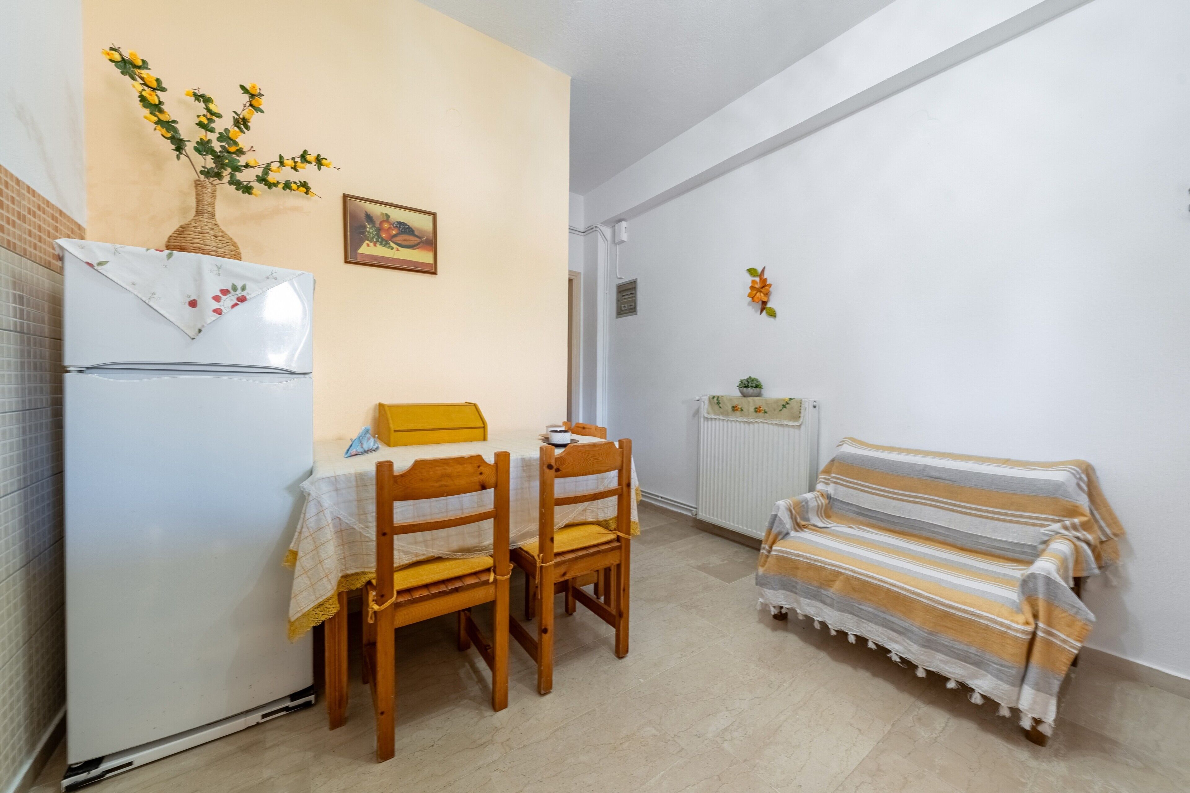 Un espace de vie compact comprenant un coin cuisine, une table à manger avec des chaises, un canapé et un radiateur.