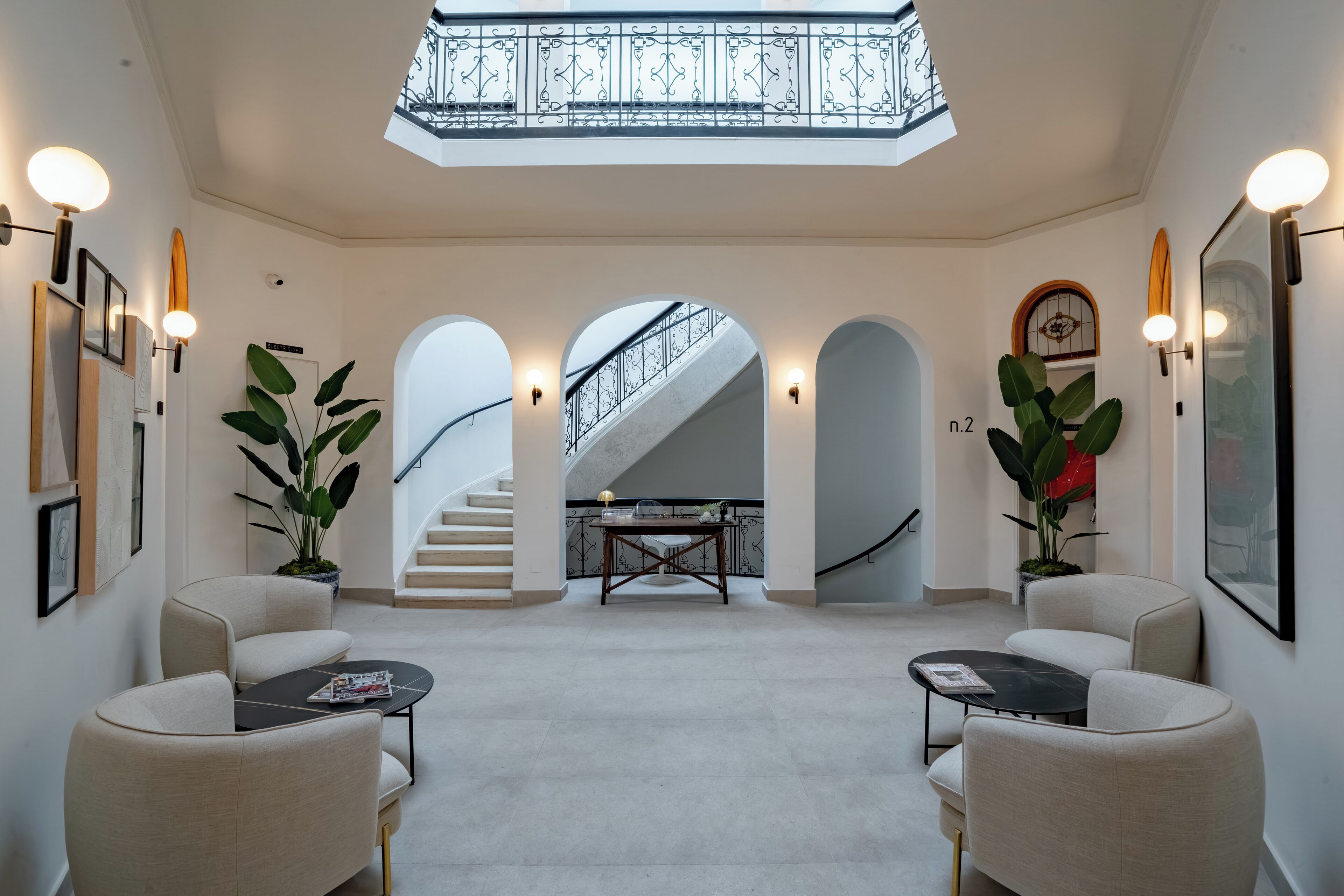 A spacious lobby with a high ceiling, a staircase, and a skylight.
