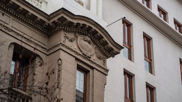 Un edificio con características arquitectónicas clásicas, incluyendo un cornisa destacada, molduras decorativas y una serie de ventanas uniformemente espaciadas.