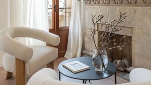 Quarto com lareira, espelho e duas cadeiras.