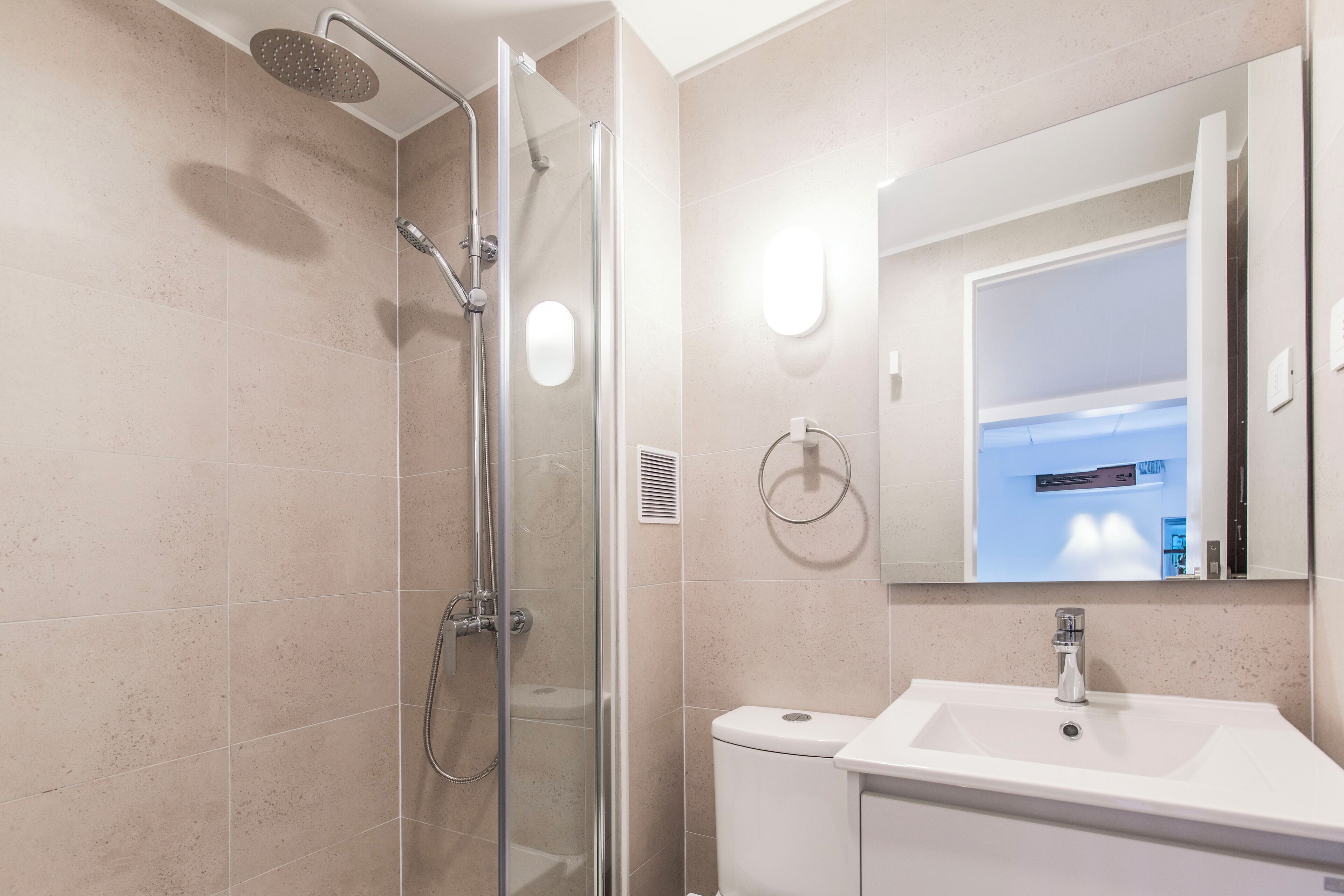 A modern bathroom with a glass-enclosed shower, a white sink, and a large mirror.
