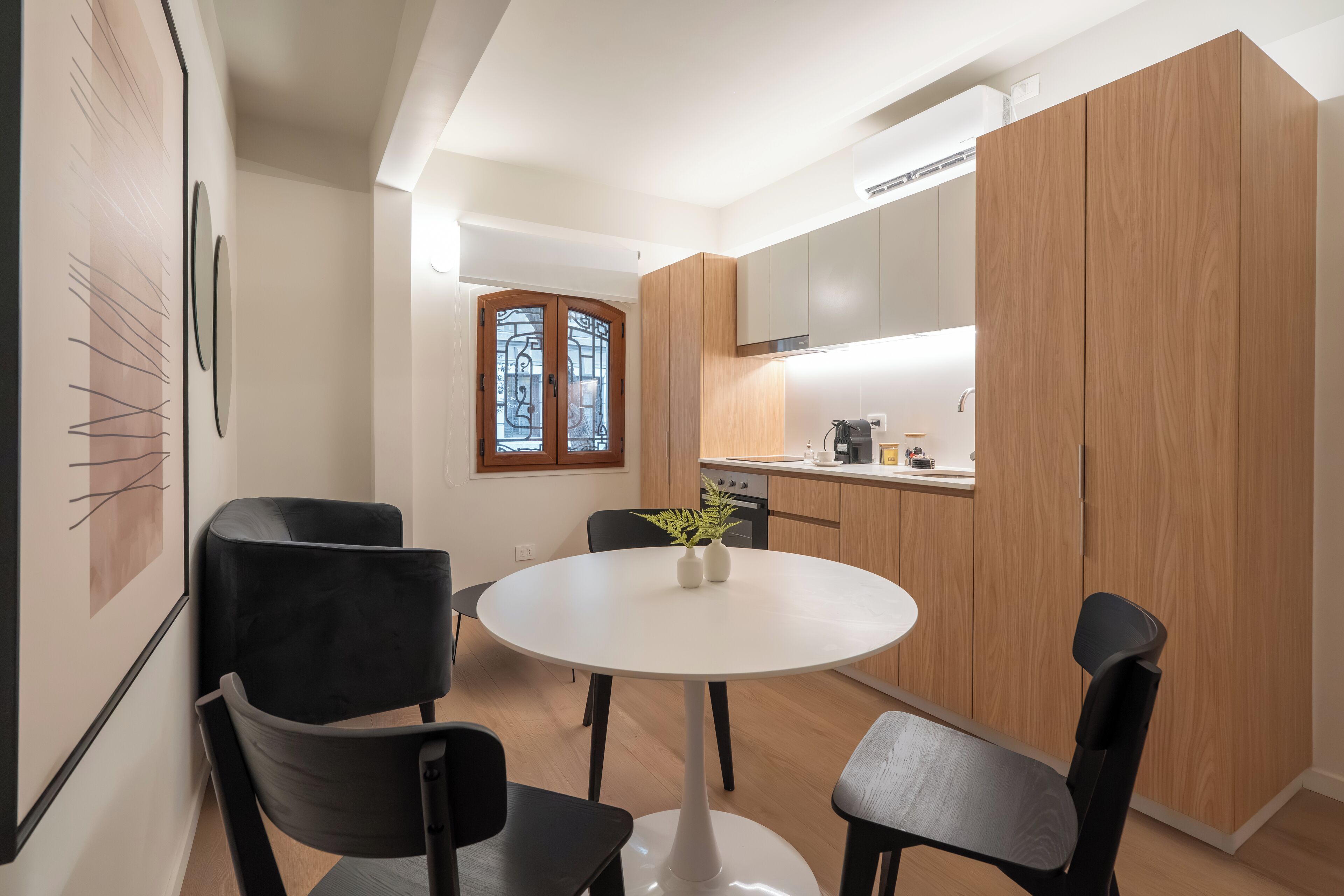 A compact kitchen with wooden cabinets, a white countertop, and a round dining table with four chairs.