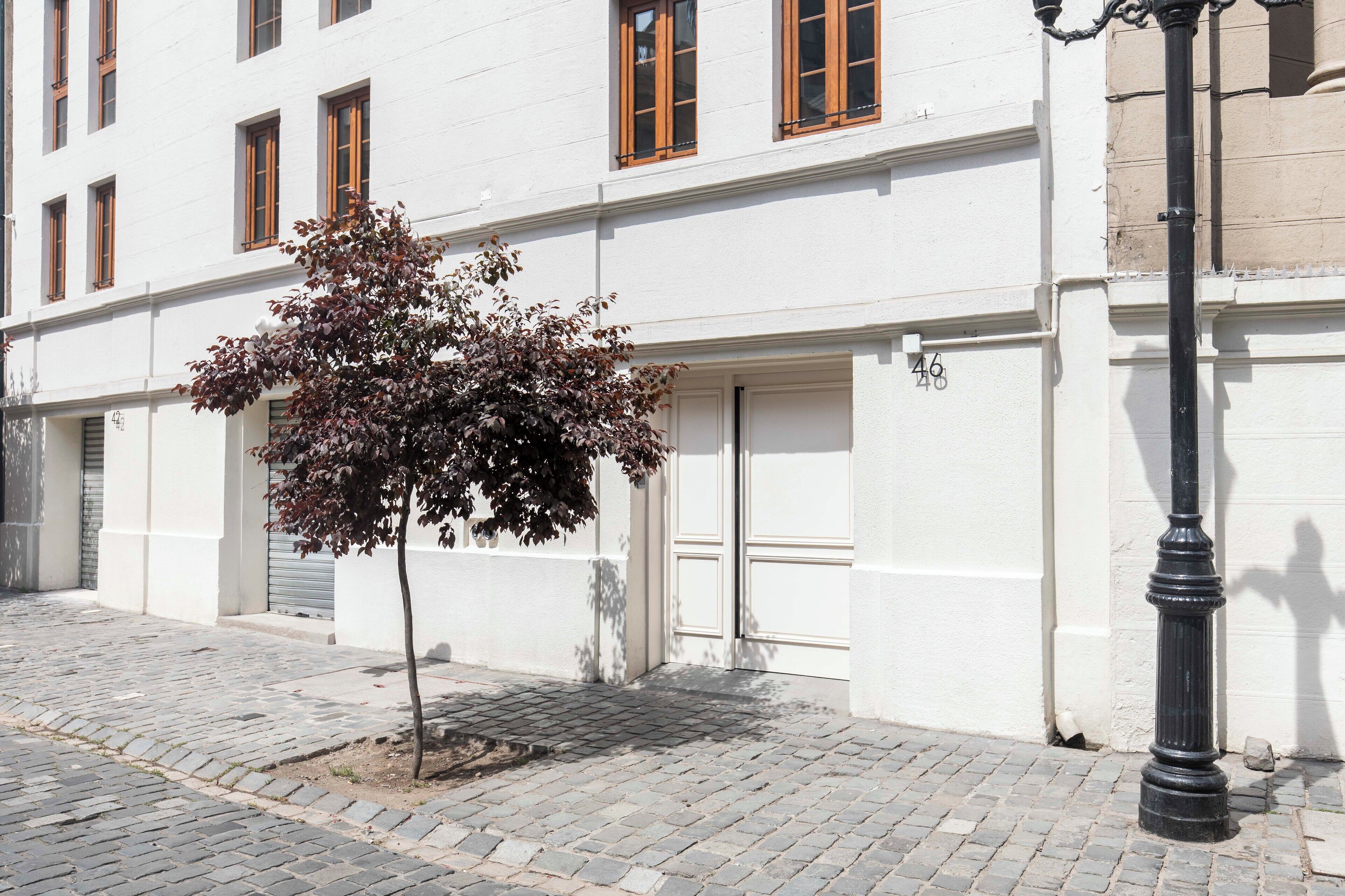Un bâtiment à la façade blanche, avec un arbre devant et un lampadaire noir.