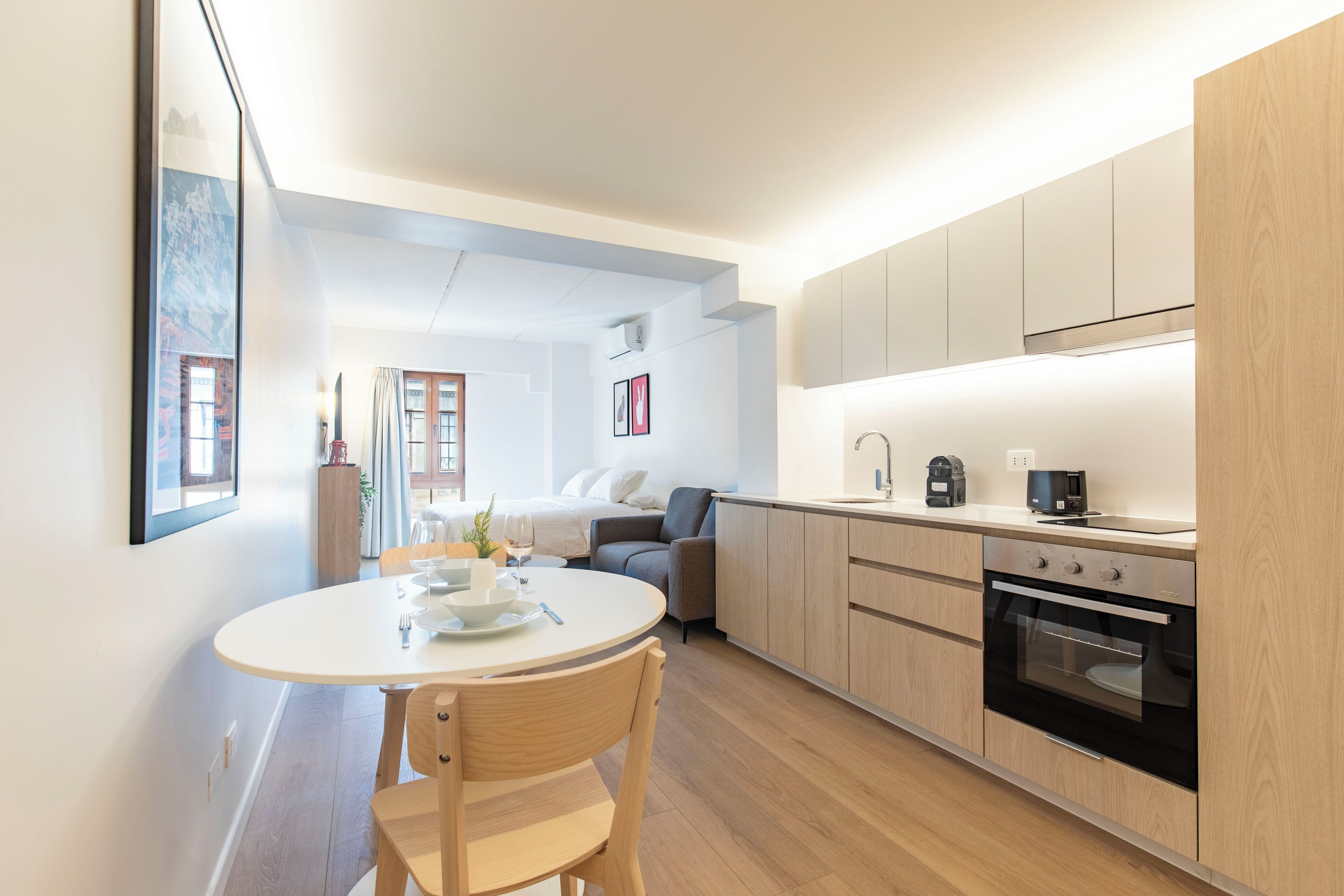 Eine moderne Küche mit Holzausstattung, einem eingebauten Backofen und einem Essbereich mit rundem Tisch und Stühlen.