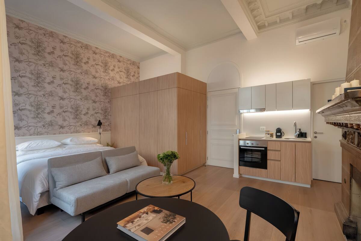 A modern, compact living space with a bed, sofa, and kitchenette.