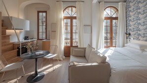 Quarto de hotel moderno com sofá, mesa de jantar e cozinha.