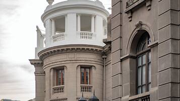 Un bâtiment historique doté d’une tour ronde, de grandes fenêtres et d’un balcon orné de balustrades.