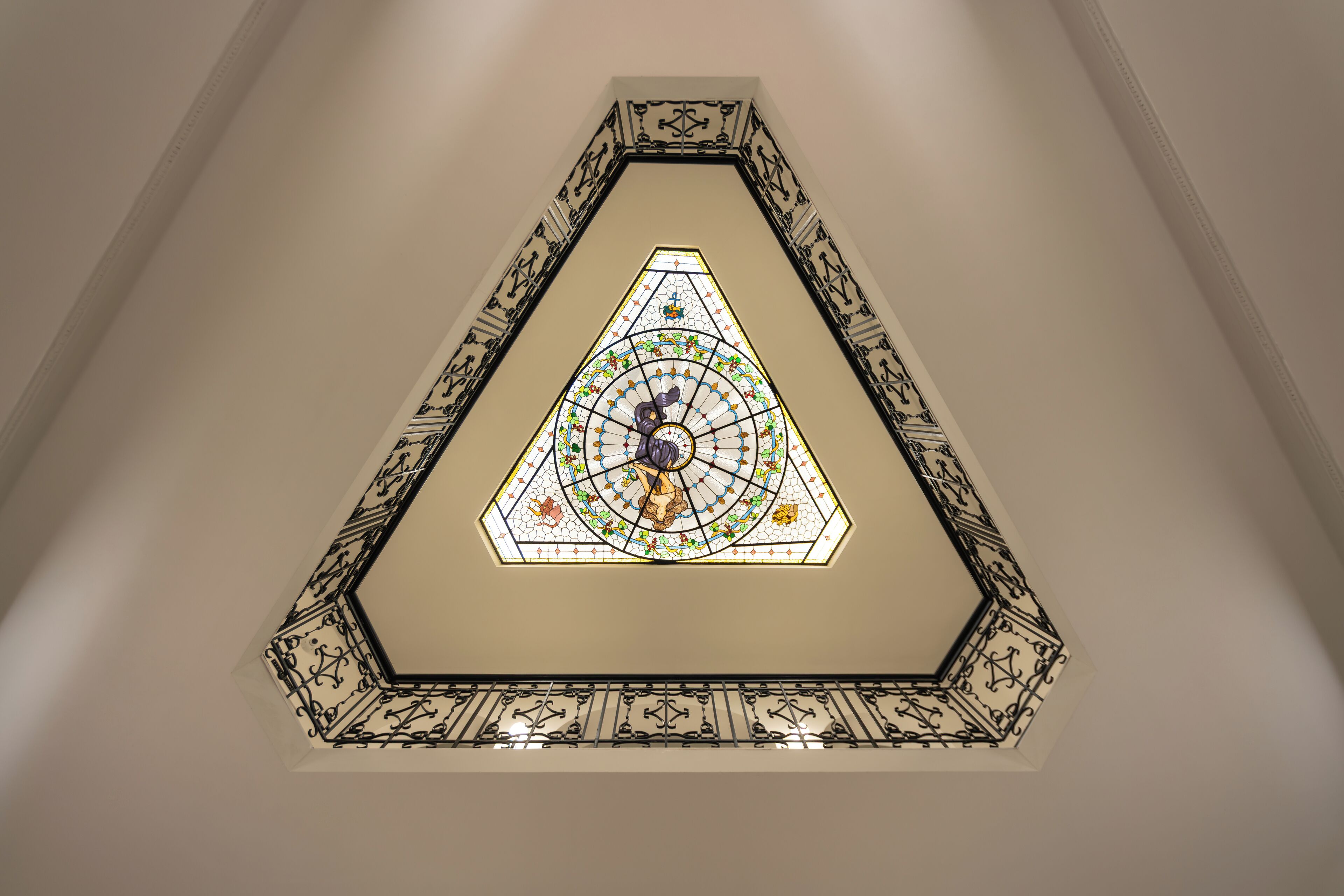 A hexagonal stained glass window with a geometric design, surrounded by a decorative metal frame.