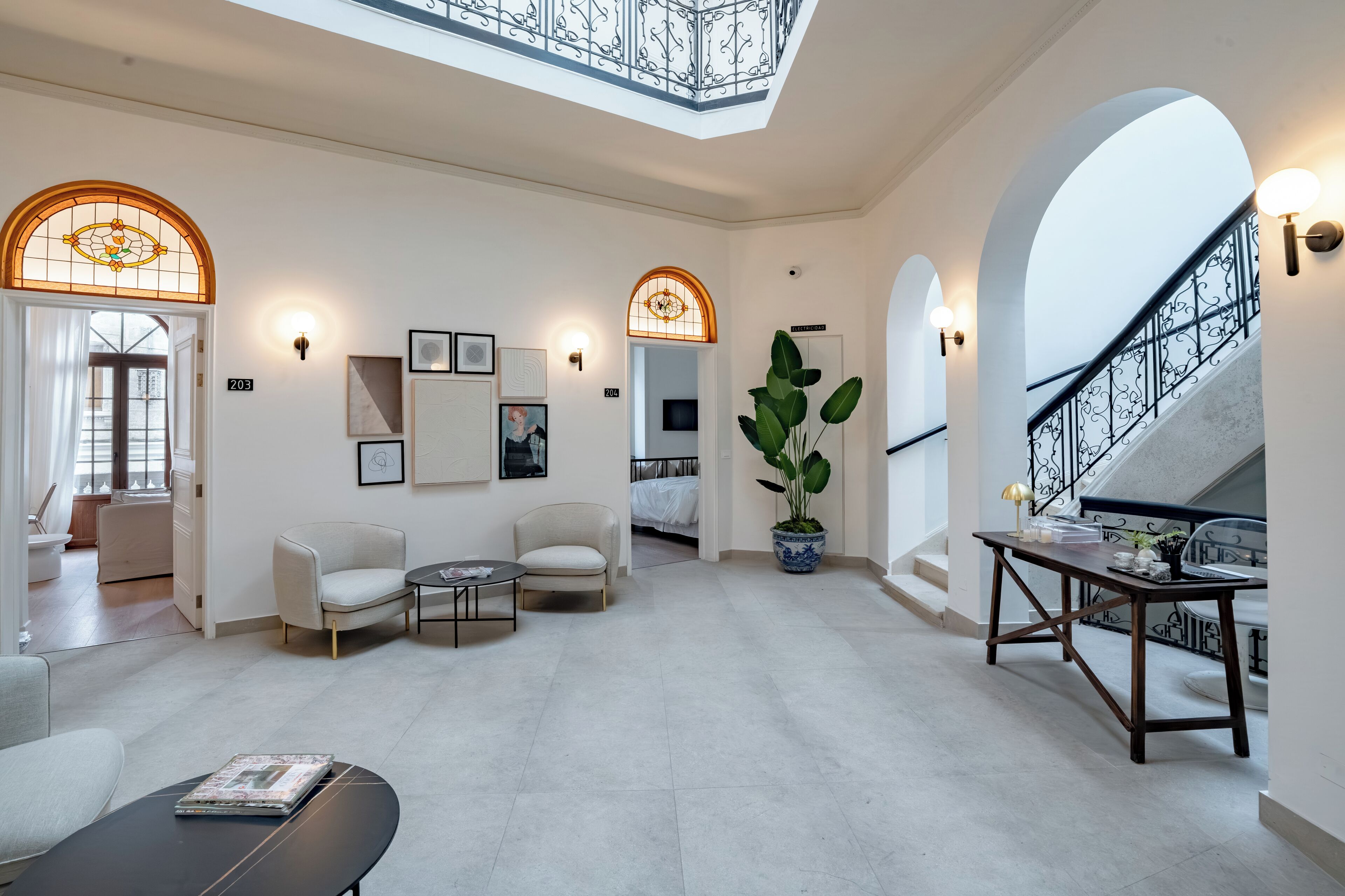 Un vaste espace de vie doté d’un haut plafond, de portes en arc de cercle et d’un escalier orné d’une rampe en fer forgé.