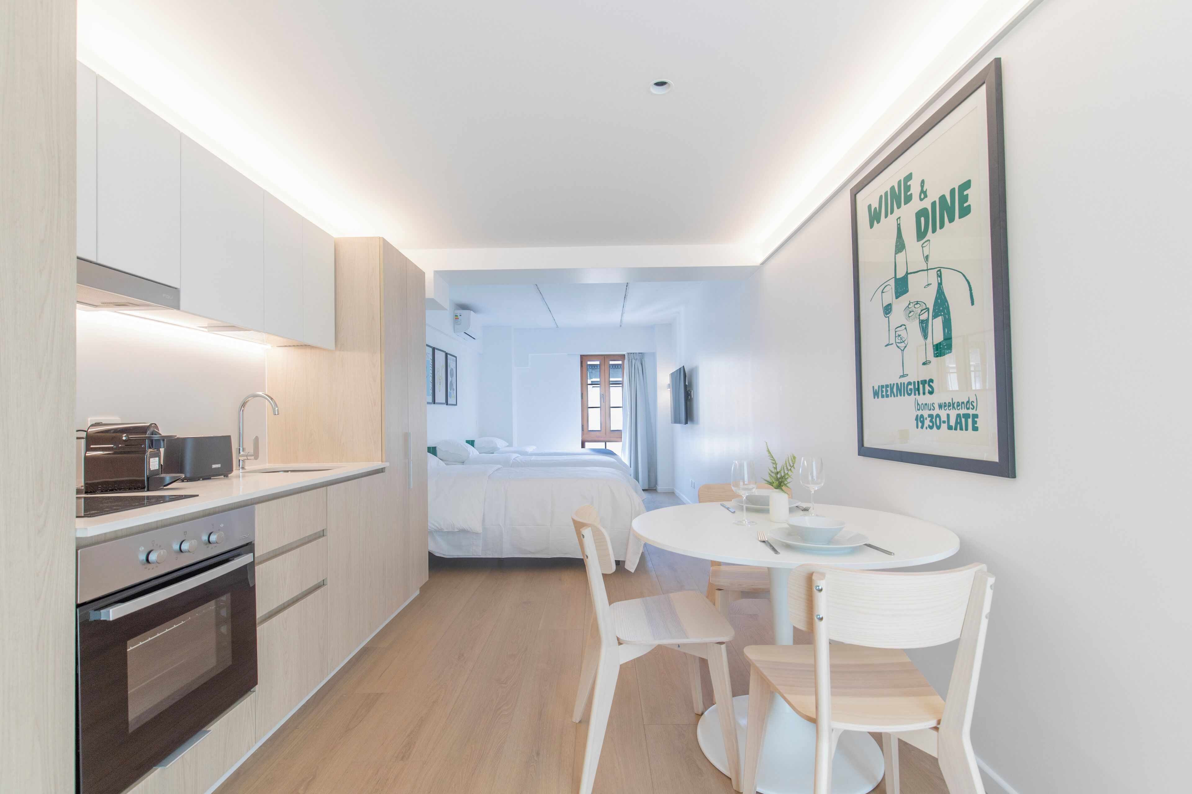 Une cuisine moderne avec un coin repas, un lit et une affiche faisant la publicité de services de restauration et de dégustation de vins.