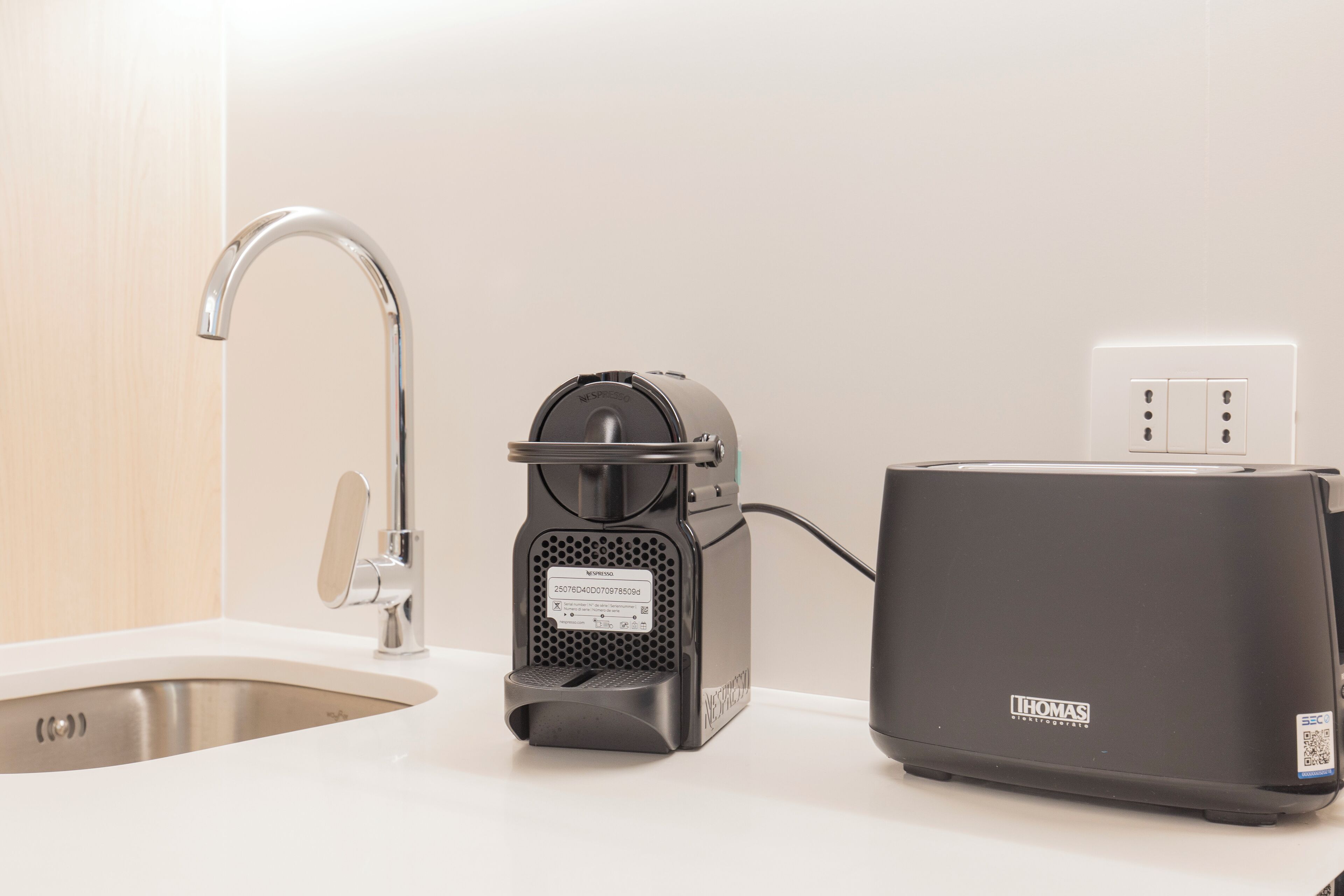 A kitchen with a coffee machine, a toaster, and a sink.