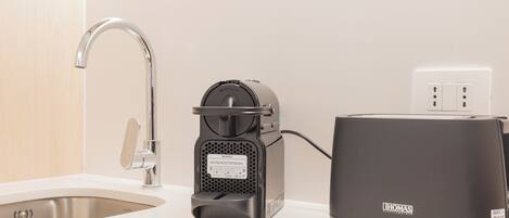 A kitchen with a coffee machine, a toaster, and a sink.
