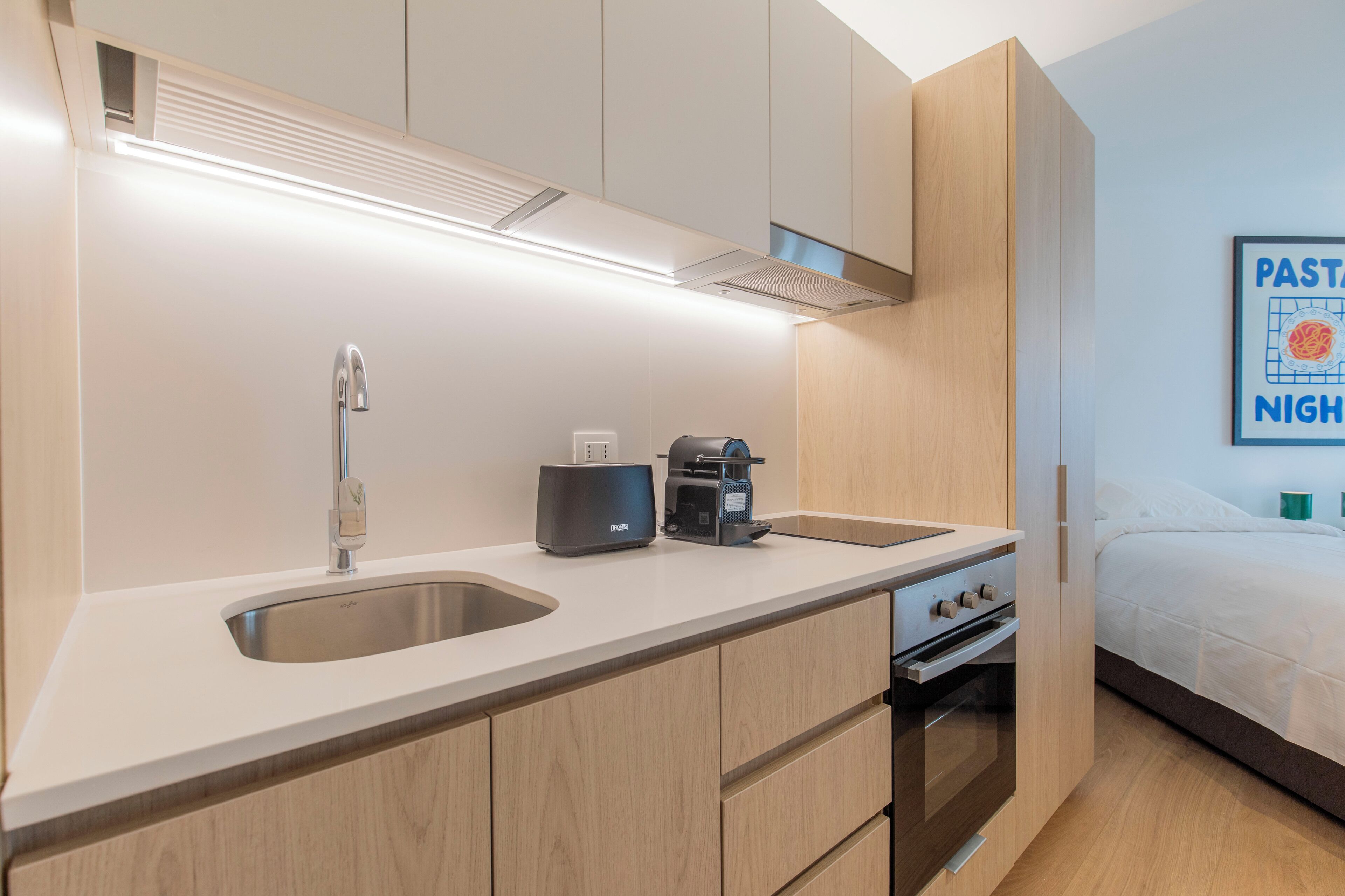 Una kitchenette compacta con un lavamanos, una cafetera y una estufa.