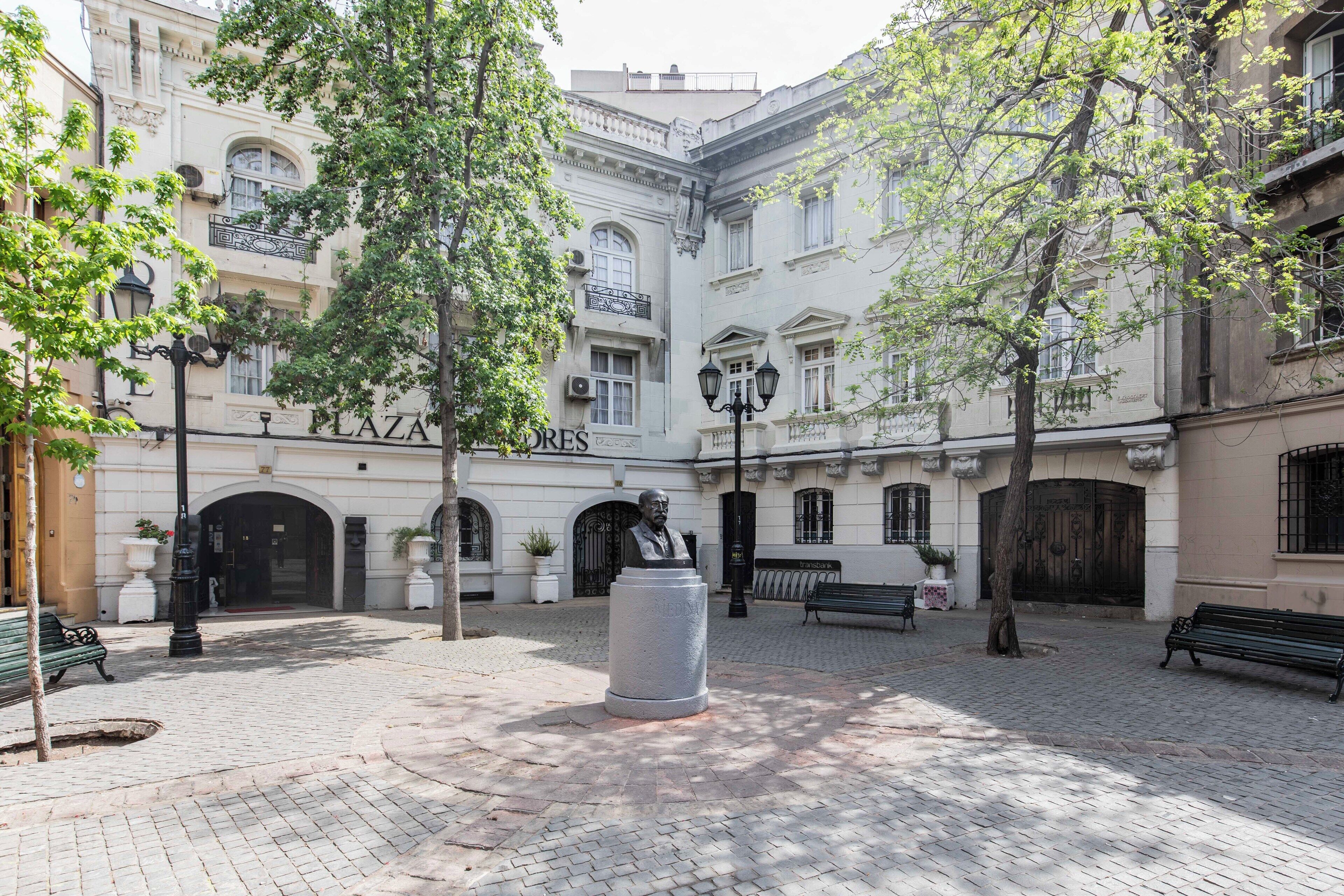Ein Platz mit einer Statue, Bänken und einem Gebäude mit der Beschilderung 'LAZARE'.