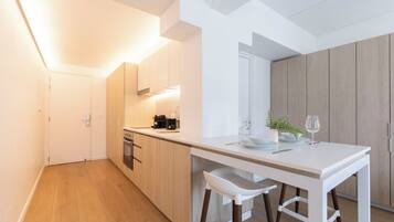 Een moderne keuken met een wit aanrecht, houten kastjes en een barkruk.