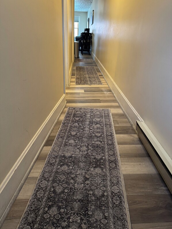 A hallway with patterned rugs and wooden flooring.