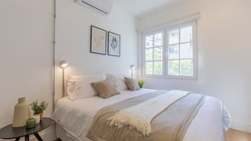 Una camera da letto con un letto, comodini, una finestra e condizionatore d'aria a parete.