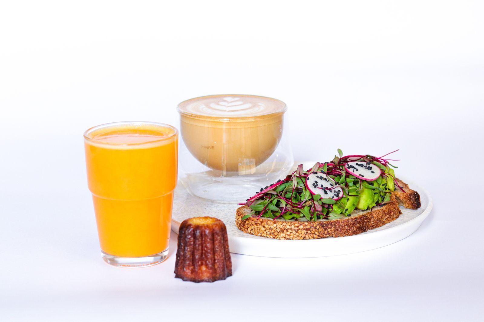 A breakfast setting with a glass of orange juice, a cup of coffee, and a plate of toast topped with vegetables and seeds.