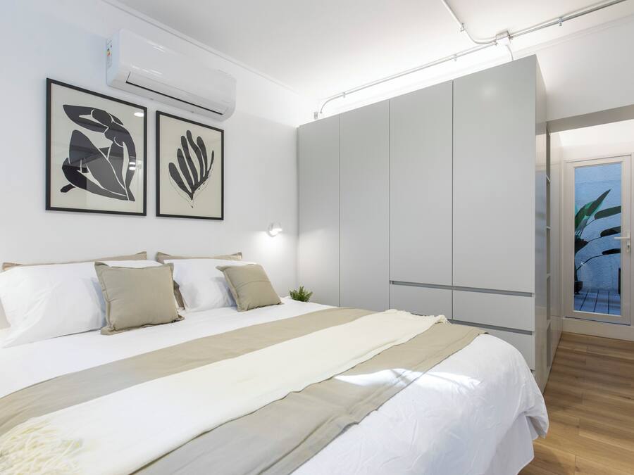 Un dormitorio moderno con una cama grande, paredes blancas y un armario.