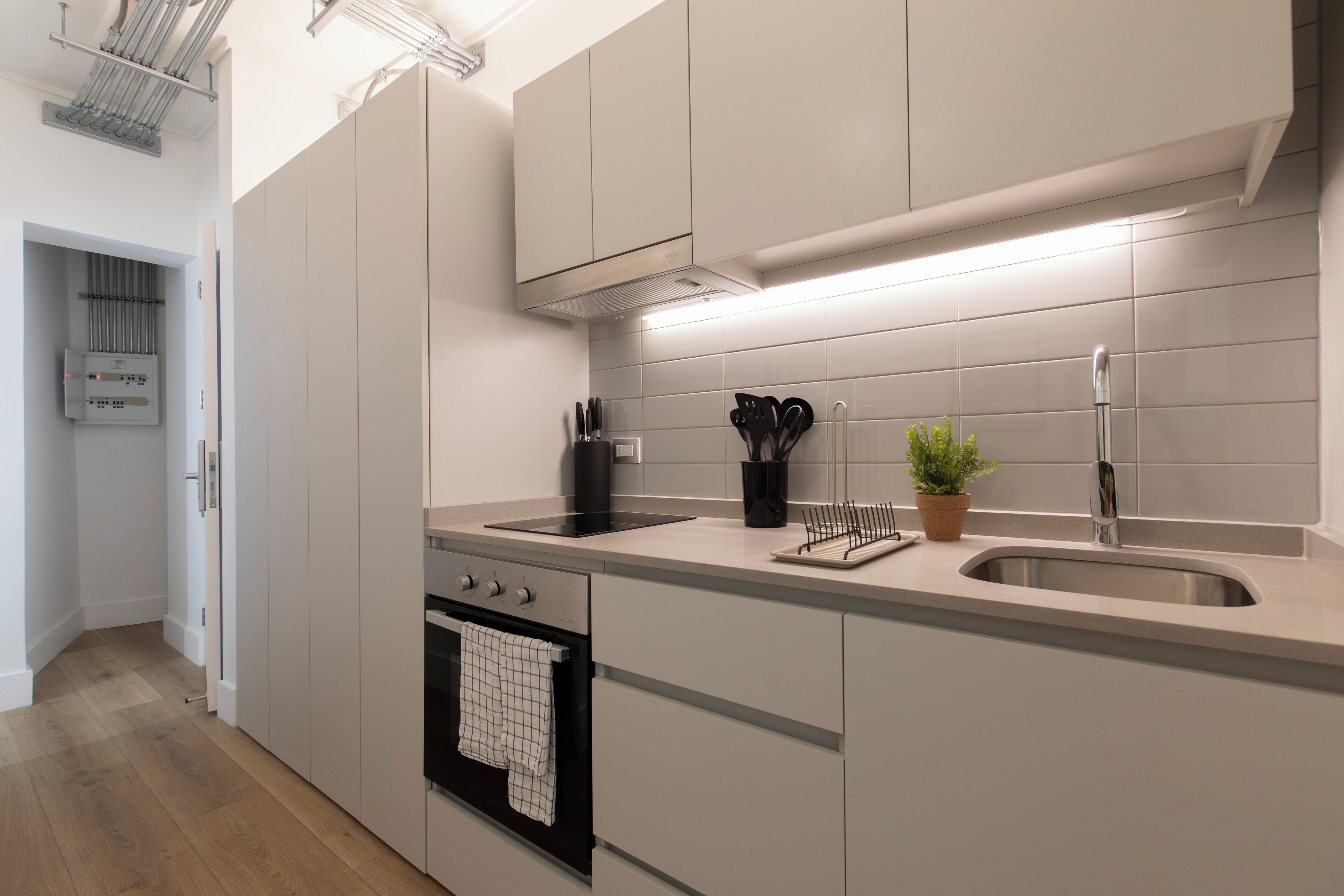 Een moderne keuken met witte kastjes, een roestvrijstalen spoelbak en een inbouwoven.