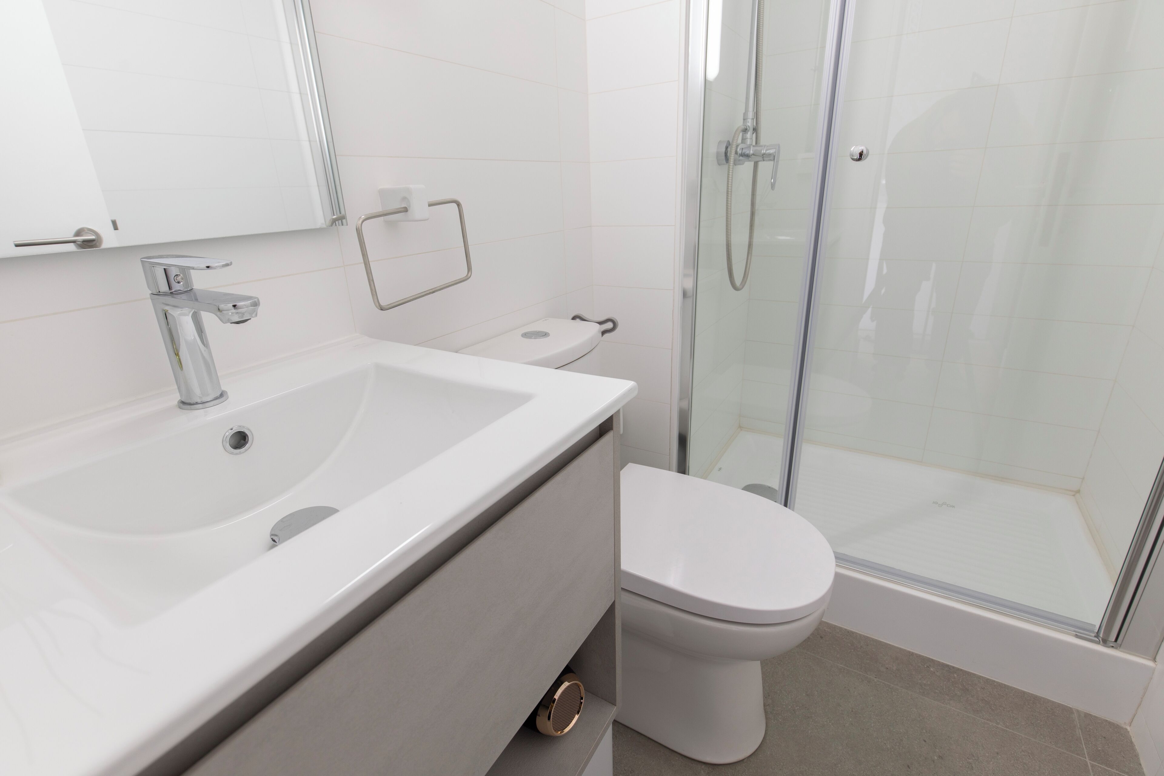 A modern bathroom with a large sink, toilet, and glass shower enclosure.