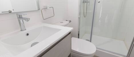 A modern bathroom with a large sink, toilet, and glass shower enclosure.