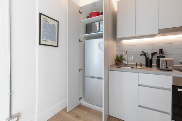 A modern kitchen with white cabinets, a built-in microwave, and a stainless steel range hood. - Nest Bellas Artes (Santiago)