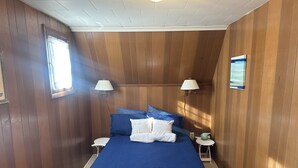Ein Schlafzimmer mit einem großen Bett, zwei Nachttischen, einem Fenster und einer Wandlampe.